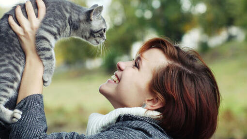 Dame lächelt und schaut zu ihrer Katze auf